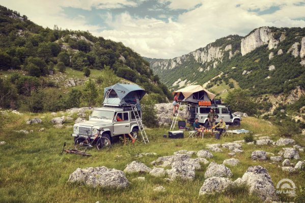 Автотуристы с палатками на крышах своих автомобилей в горах