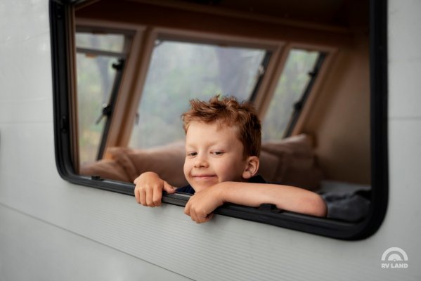 Мальчик выглядывает из окна дома на колесах